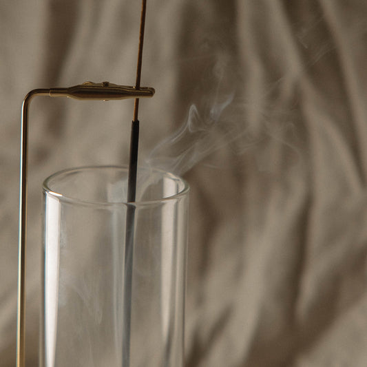 Incense stick in a glass container with smoke against a blurred background
